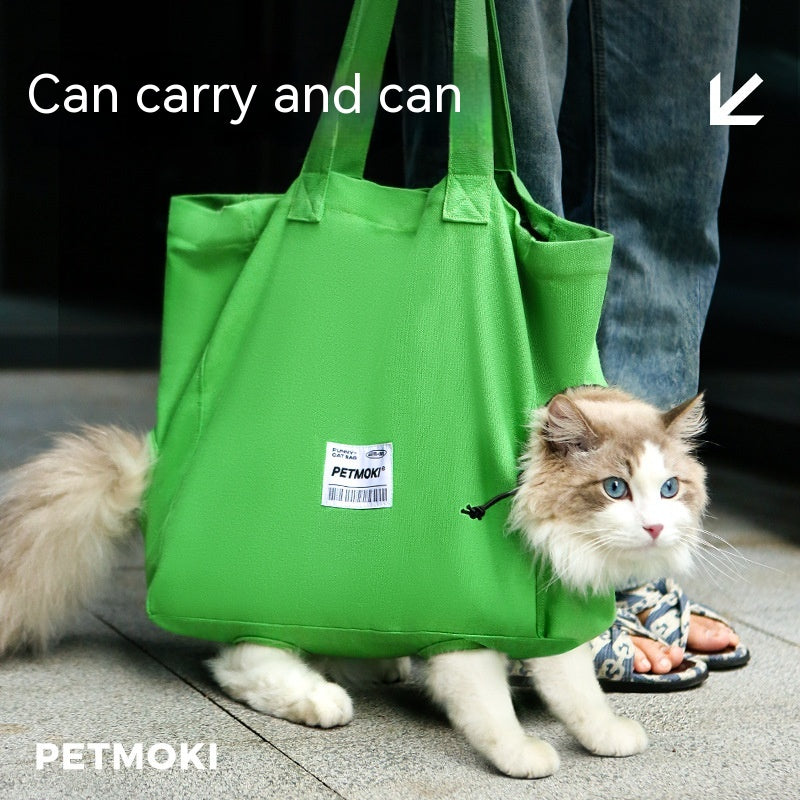 Cat peeking out of green canvas carrier, outdoor scene